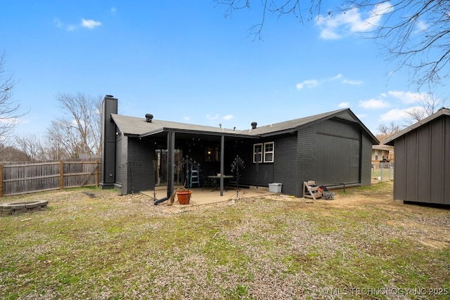 rear view of house featuring a patio area, brick siding, fence, and a chimney