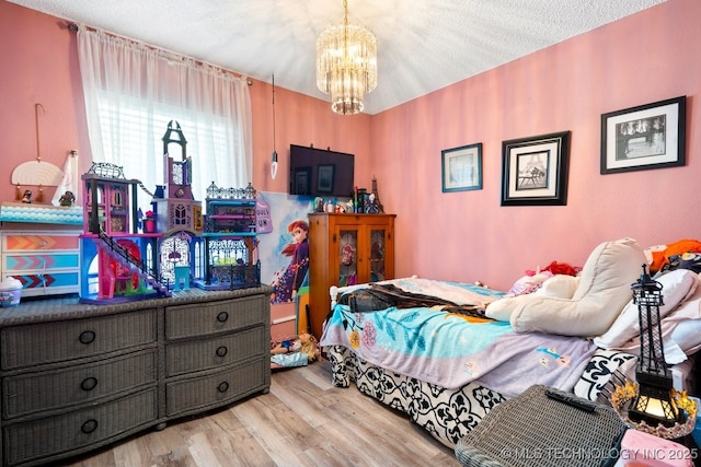 bedroom with a notable chandelier, a textured ceiling, and wood finished floors