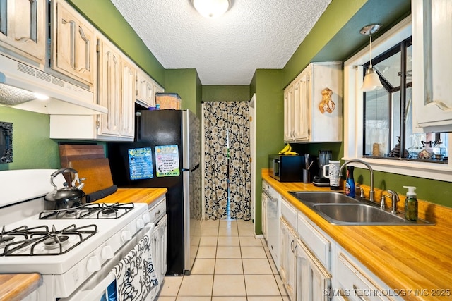 kitchen with light tile patterned floors, white gas range, under cabinet range hood, black microwave, and a sink