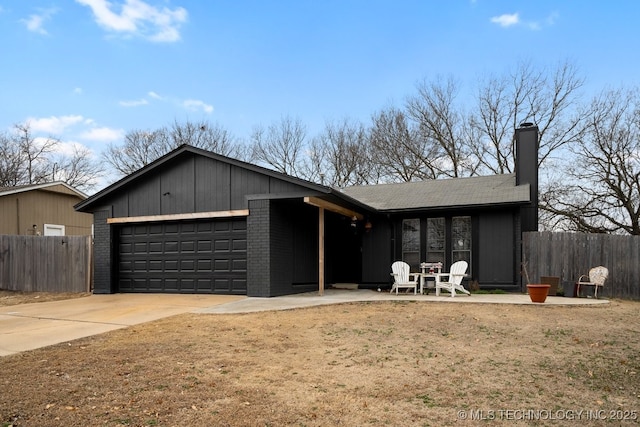 view of front of property with a garage, driveway, fence, and brick siding