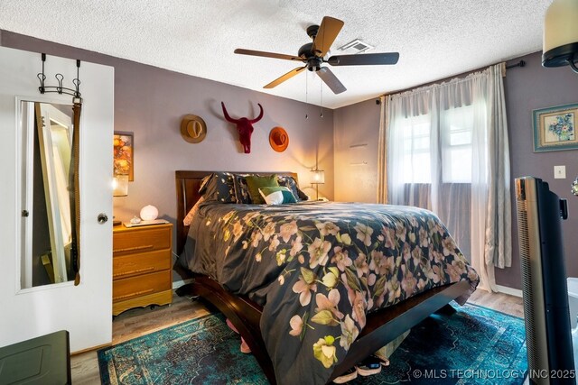 bedroom with a textured ceiling, wood finished floors, and visible vents