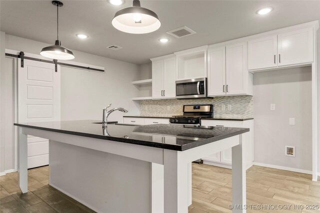 kitchen with stainless steel appliances, a barn door, light wood-style flooring, and visible vents