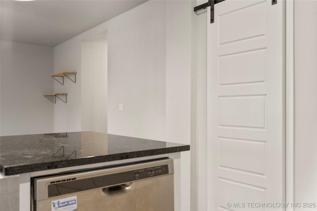 kitchen with a barn door, dark stone counters, open shelves, and dishwasher