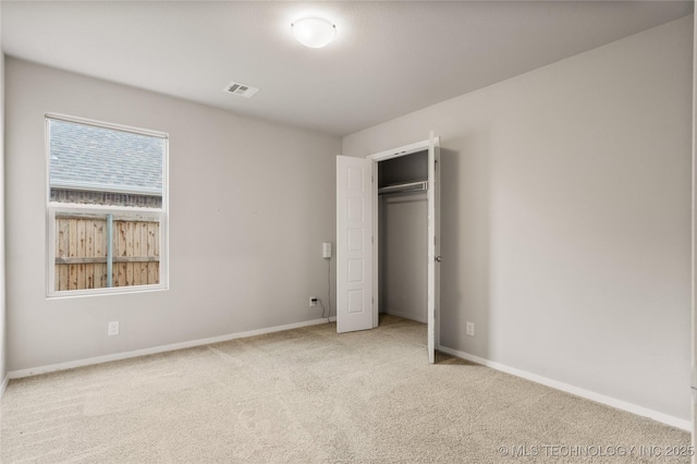 unfurnished bedroom with carpet, a closet, visible vents, and baseboards