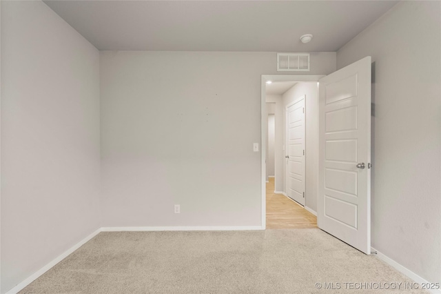 empty room with light colored carpet, visible vents, and baseboards