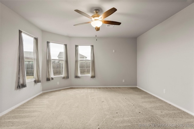 carpeted empty room featuring a ceiling fan, visible vents, and baseboards