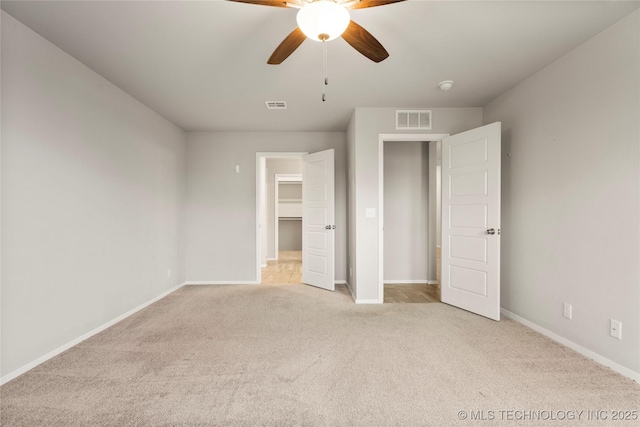 unfurnished bedroom with carpet, visible vents, a walk in closet, and baseboards