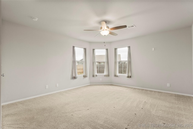 empty room with carpet, visible vents, ceiling fan, and baseboards