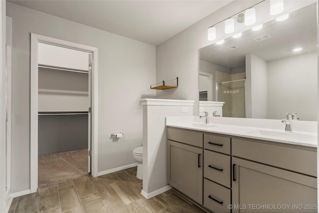 bathroom featuring toilet, a sink, visible vents, a shower stall, and double vanity