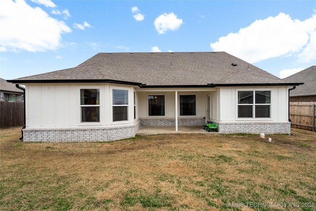 rear view of property with a yard, a shingled roof, and fence