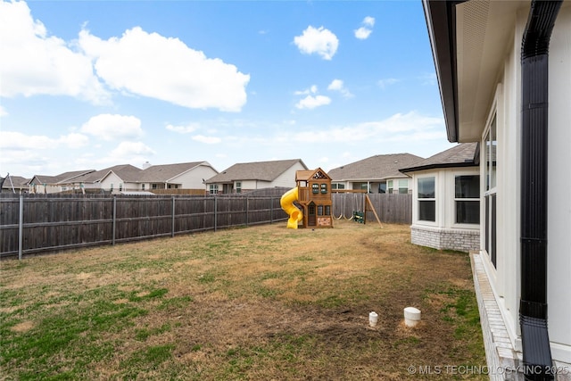 view of yard featuring a residential view, a fenced backyard, and a playground