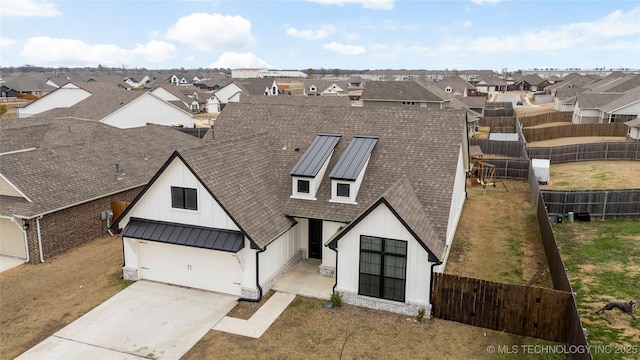 view of front facade with metal roof, concrete driveway, roof with shingles, a residential view, and a standing seam roof