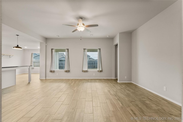 empty room featuring baseboards, plenty of natural light, a ceiling fan, and light wood-style floors