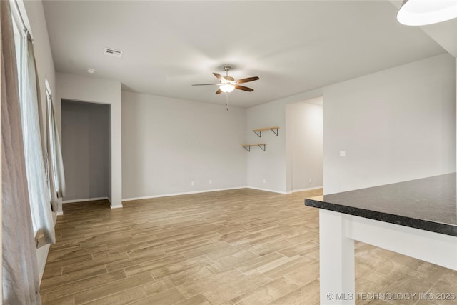 unfurnished living room featuring light wood-style flooring, visible vents, ceiling fan, and baseboards