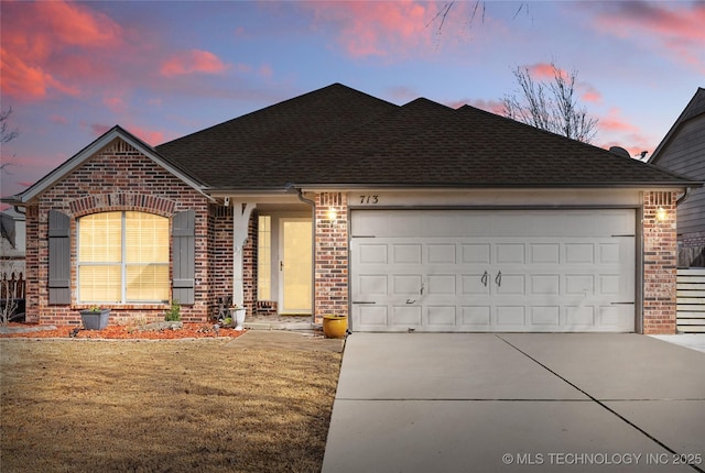 ranch-style house featuring concrete driveway, brick siding, roof with shingles, and an attached garage