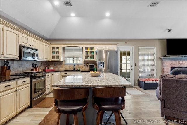 kitchen with visible vents, appliances with stainless steel finishes, open floor plan, and a kitchen breakfast bar