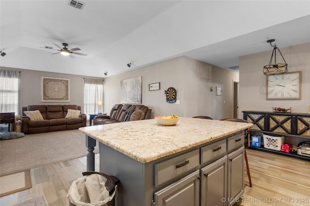 kitchen featuring a center island, a kitchen bar, visible vents, and light wood-style floors