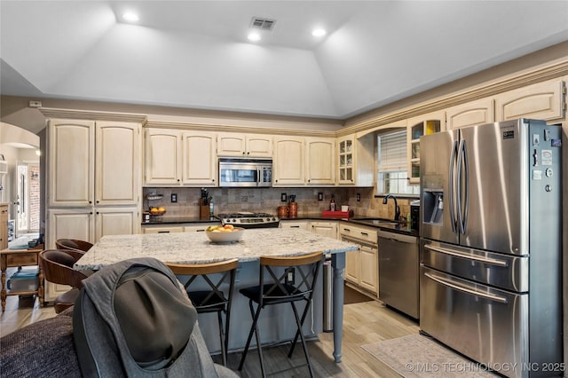 kitchen featuring visible vents, arched walkways, lofted ceiling, appliances with stainless steel finishes, and a sink