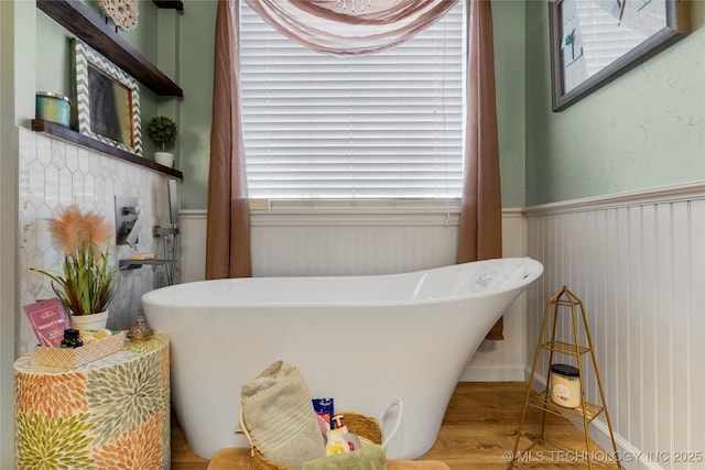 full bath with a freestanding tub, wainscoting, and wood finished floors