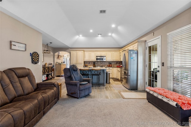 living area with light carpet, visible vents, arched walkways, lofted ceiling, and recessed lighting