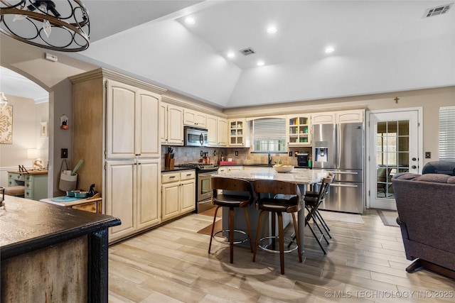 kitchen featuring stainless steel appliances, arched walkways, visible vents, and tasteful backsplash