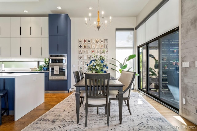 dining space featuring light wood-style floors, recessed lighting, and an inviting chandelier