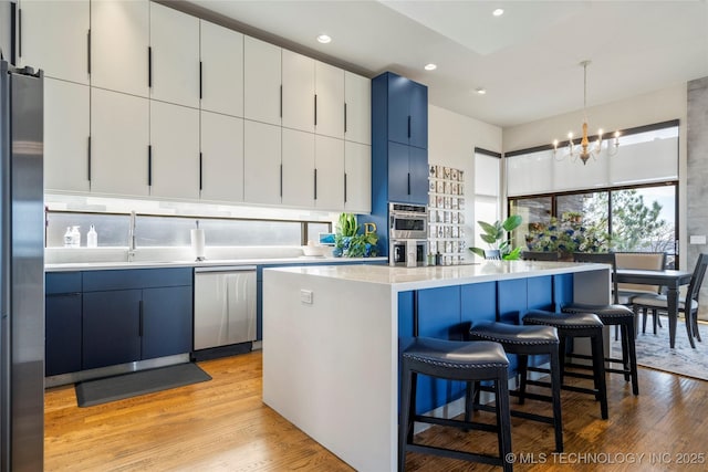 kitchen featuring a sink, light countertops, appliances with stainless steel finishes, light wood-type flooring, and a center island