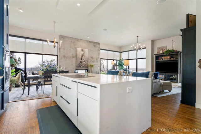 kitchen with modern cabinets, wood finished floors, a kitchen island, and an inviting chandelier