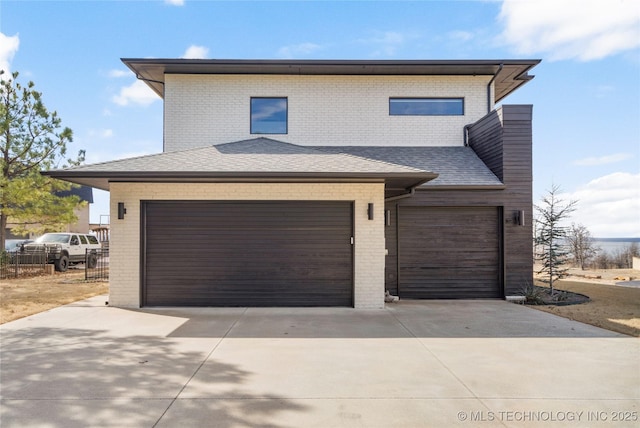 view of front of property with an attached garage, a shingled roof, concrete driveway, and brick siding