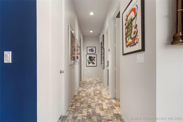 hall with recessed lighting, stone finish flooring, and baseboards