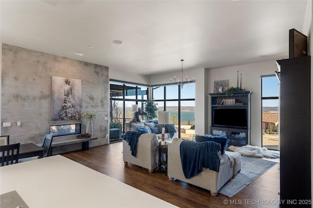 living room featuring dark wood-style floors, a notable chandelier, and a tiled fireplace