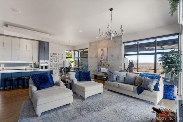 living area with a healthy amount of sunlight, wood finished floors, and an inviting chandelier