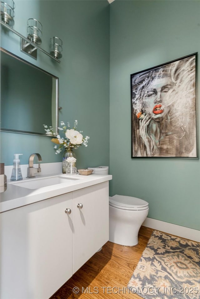 bathroom with vanity, wood finished floors, toilet, and baseboards