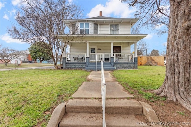 view of front facade featuring a front lawn, a chimney, and a porch