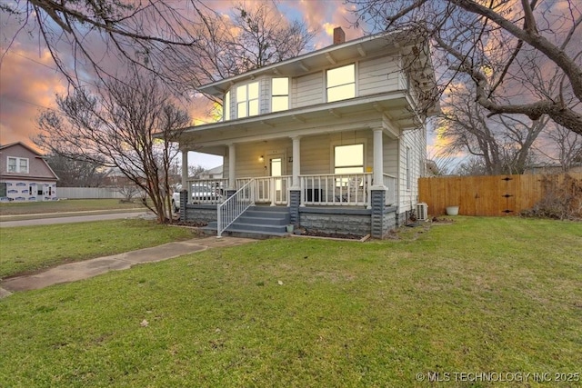 view of front facade featuring a porch, a front lawn, a chimney, and fence