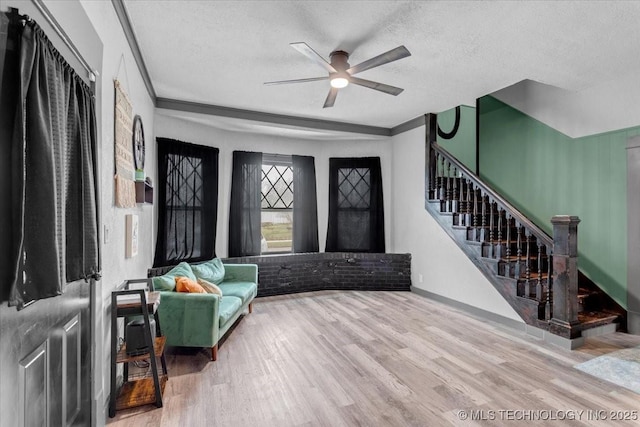 sitting room with baseboards, ceiling fan, stairway, wood finished floors, and a textured ceiling