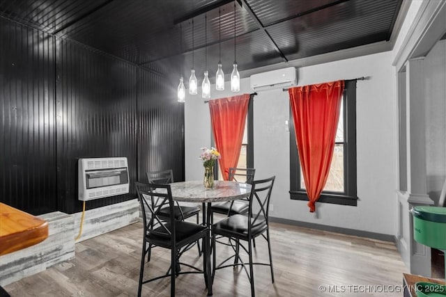 dining space with an AC wall unit, baseboards, heating unit, and wood finished floors