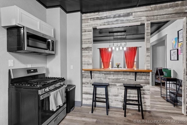 kitchen featuring appliances with stainless steel finishes, a breakfast bar area, light wood-type flooring, and white cabinets