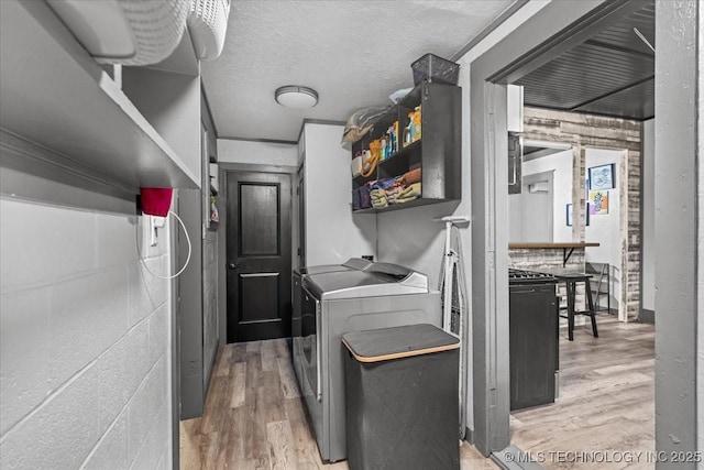 laundry room featuring light wood-type flooring, laundry area, a textured ceiling, and separate washer and dryer