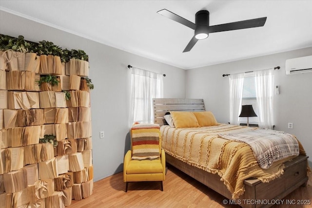 bedroom featuring light wood-style floors, ceiling fan, and a wall mounted AC