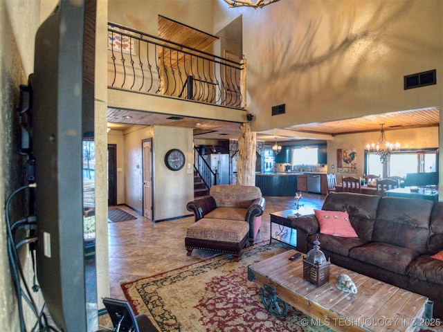 living area with stairs, visible vents, a towering ceiling, and an inviting chandelier