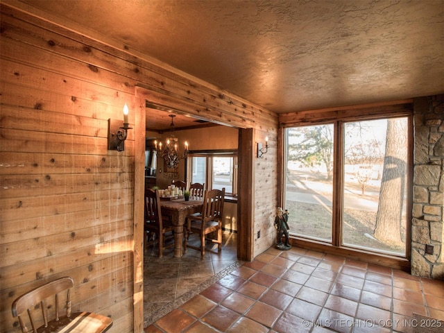 dining room featuring wood walls, a textured ceiling, and a notable chandelier