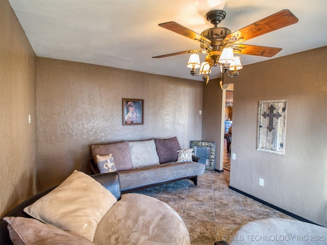 living area with ceiling fan, a textured wall, baseboards, and tile patterned floors