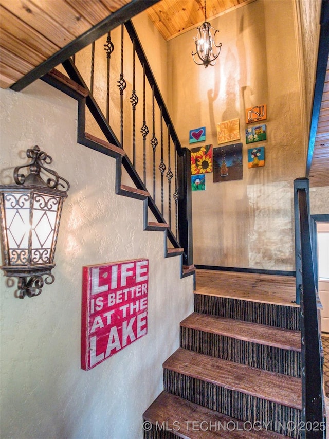 staircase with wood ceiling, a notable chandelier, and a textured wall