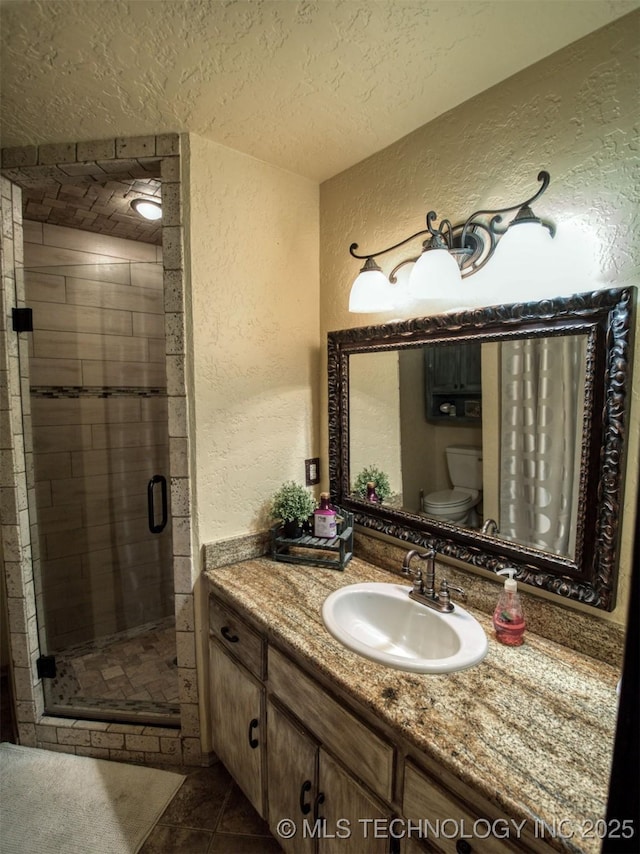 bathroom with a textured ceiling, a textured wall, toilet, vanity, and a stall shower