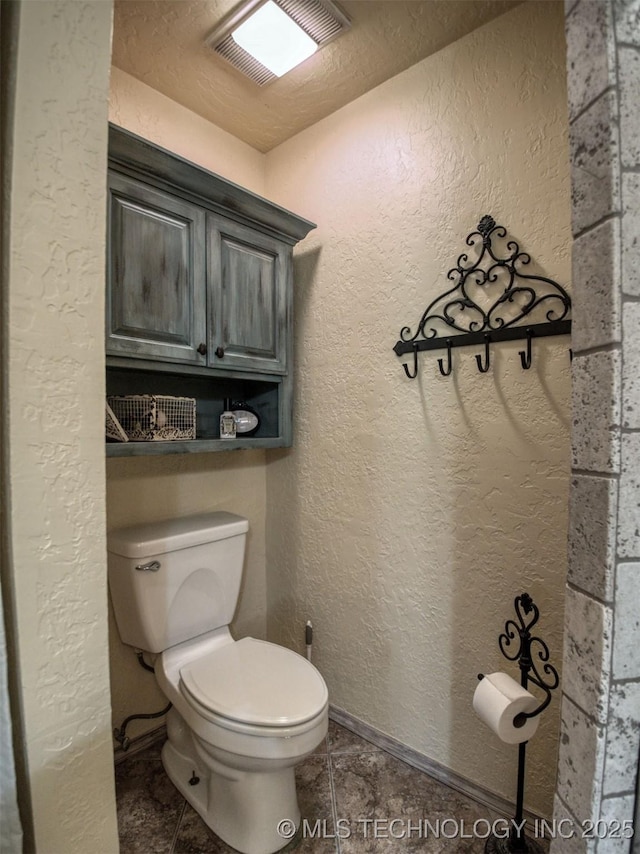 bathroom featuring toilet, a textured wall, visible vents, and tile patterned floors