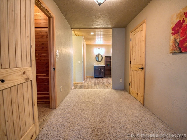 corridor with carpet floors, a textured ceiling, and a textured wall