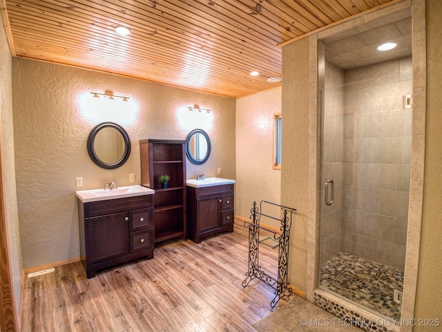 full bathroom featuring wood finished floors, a sink, and a textured wall