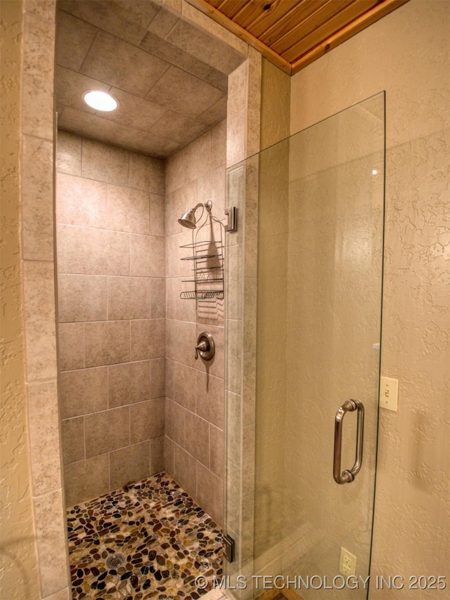 bathroom featuring a stall shower and a textured wall