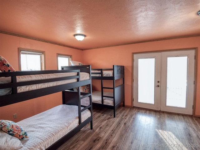 bedroom featuring ornamental molding, french doors, a textured ceiling, and wood finished floors